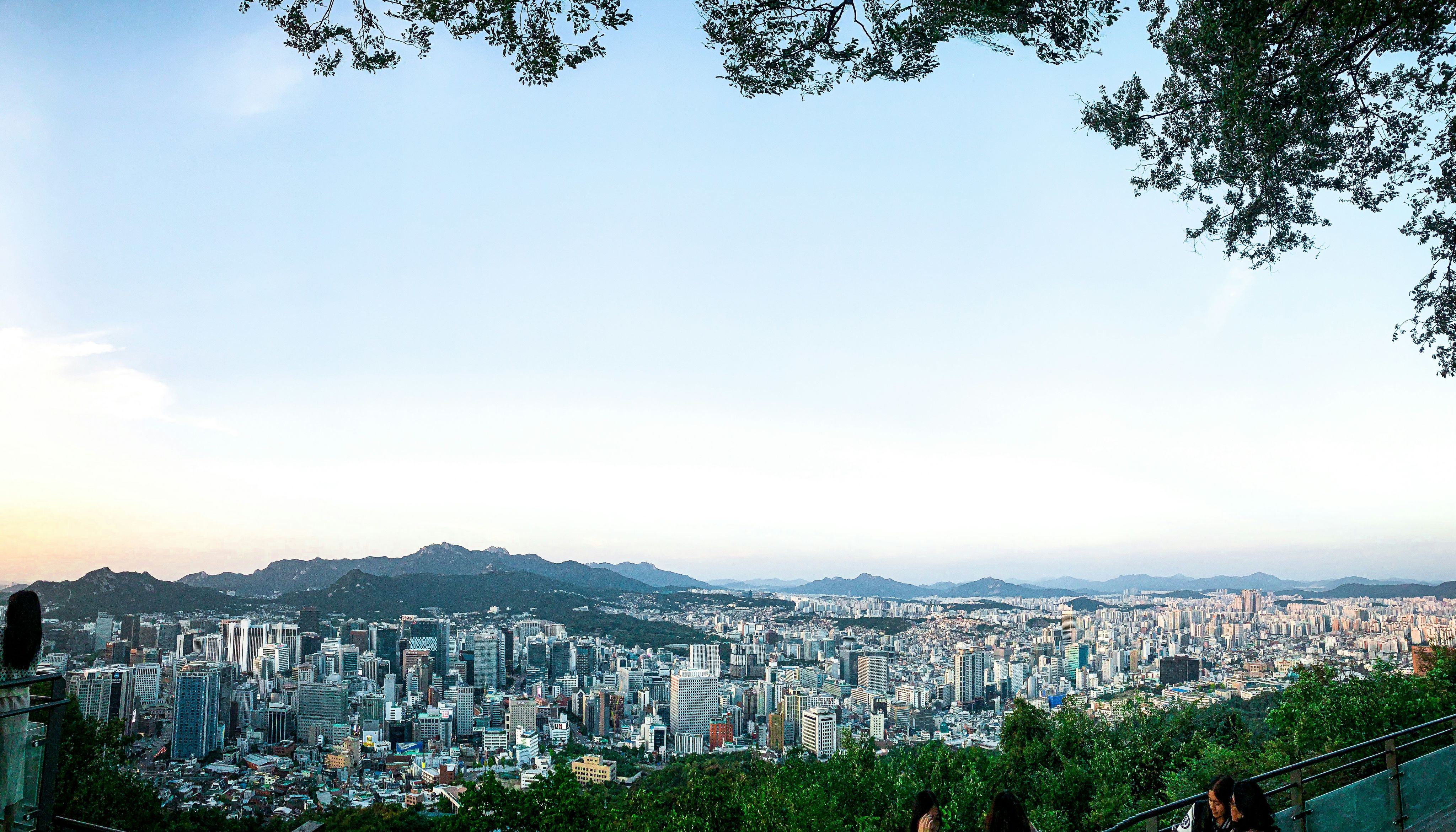 a group of people sitting on a bench overlooking a city